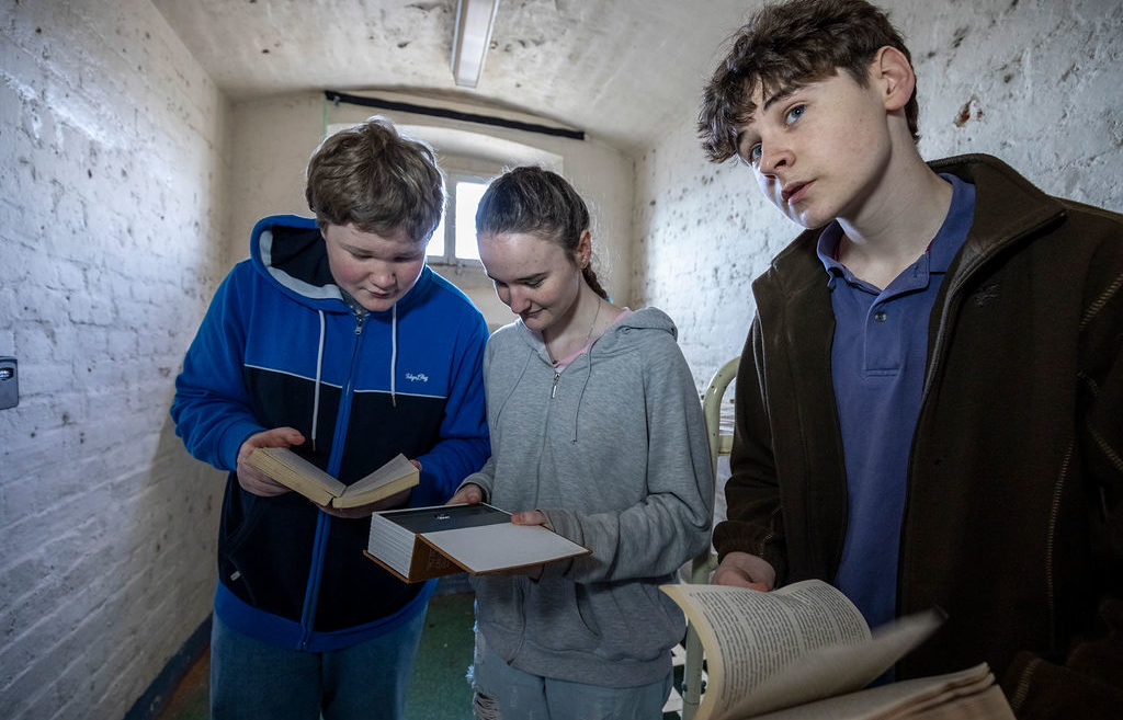 A group of visitors trying to work out a clue during The Cell Escape Room